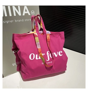 Detail of rose red canvas tote bag featuring colorful patterned straps and white print