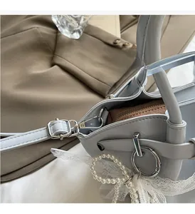 Detail of light blue pleated bucket bag with silver ring hardware and pearl charm