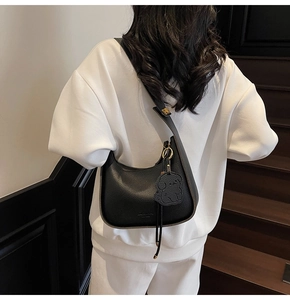 Close-up of black lychee grain leather hobo bag with cute bear charm detail