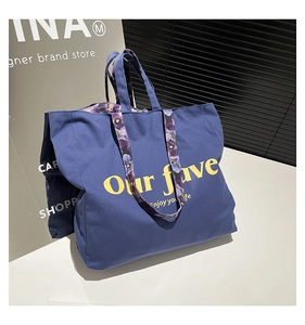Detail view of navy blue canvas tote bag with yellow lettering and floral straps