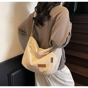 Model wearing the beige canvas tote bag with adjustable strap and leather logo patch