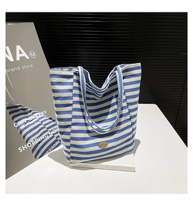 Close-up of blue and white striped tote bag with handmade gold metal nameplate detail