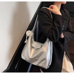 Gros plan du sac demi-lune argenté métallisé avec pompon blanc sur les escaliers
