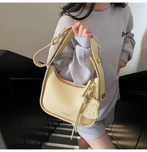 Detail of cream lychee texture hobo bag with adjustable strap and bear charm