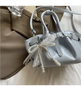 Detail of light blue pleated bucket bag featuring pearl bow and lace charm accessory