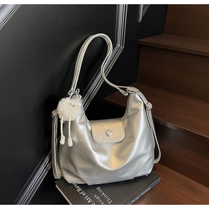 Détail du sac hobo argenté métallisé avec charme en peluche sur des livres design