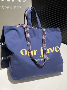 Blue canvas tote bag with yellow text and purple floral shoulder strap in main view