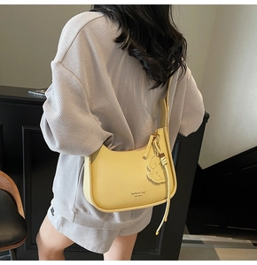 Detail view of yellow lychee texture half-moon crossbody bag with floral pendant