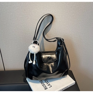 Détail du sac cabas noir brillant avec un joli pendentif monstre en peluche blanche