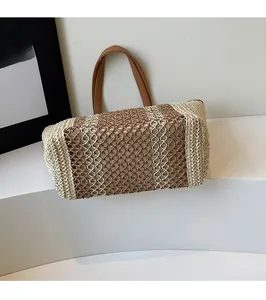 Detail showing contrast weave hollow mesh and brown leather handles on a straw tote bag