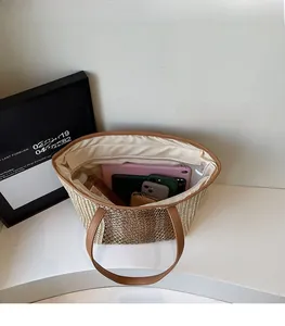 Top view of spacious straw tote interior with leather handles and daily essentials