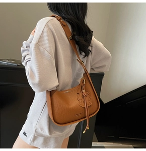 Caramel lychee grain leather shoulder bag with puppy charm and tassel shown on model