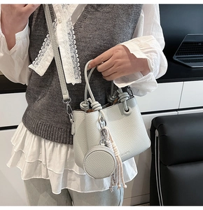 Litchi texture bucket bag with knotted handle and round coin purse charm shown on model