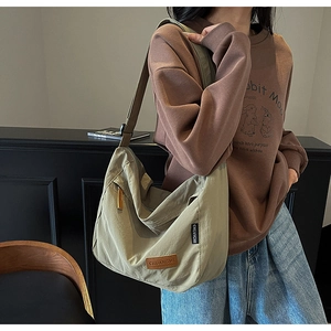 Detail of light khaki tote bag showing leather brand tag and durable nylon texture