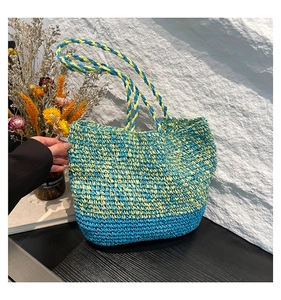 Détail de la couture contrastée bleu et vert citron sur le sac cabas en paille tressé