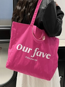 Hot pink canvas tote bag with Enjoy Your Life lettering shown on a female model