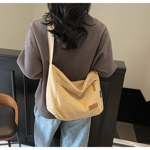Detail of minimalist beige canvas tote bag with brown leather logo patch for commuting