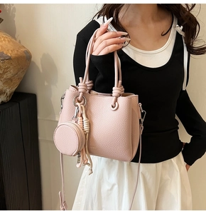 Detail of light pink pebble leather bucket bag with matching round coin purse and gold hardware