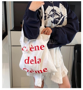 Détail du sac cabas blanc avec texte rouge Crème de la Crème et texture en toile épaisse