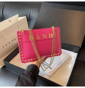 Close-up of fuchsia textured leather envelope bag with gold AND logo and chain strap