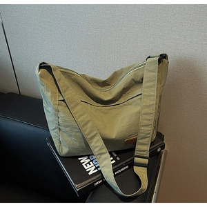 Detail view of olive green tote bag featuring a leather brand tag and durable nylon fabric