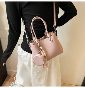 Close-up of pink bucket bag featuring litchi texture with mini purse and tassel detail
