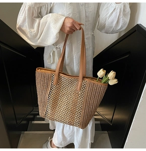 Detail of hollow woven straw tote bag with brown leather handles and yellow lining
