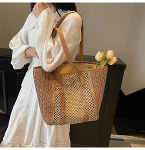 Detail of hollow-out straw tote bag with brown leather handles and interior fabric lining