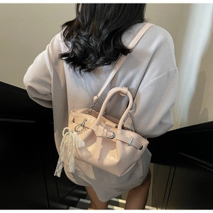 Detail view of pink bucket bag with pearl pendant and lace bow on a beige outfit