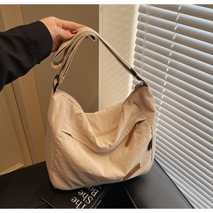 Detail of beige nylon tote bag showing textured fabric and external zipper pocket