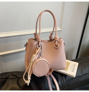 Close-up of pink litchi grain leather bucket bag with coin purse and woven tassel