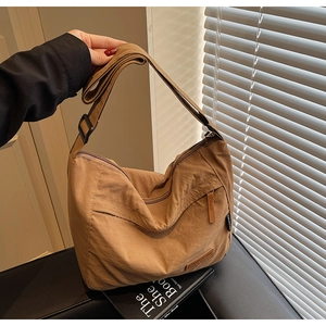 Detail of caramel nylon crossbody bag featuring front zipper pocket and adjustable strap
