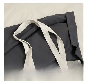 Détail des poignées renforcées et de la texture du tissu d'un sac cabas en toile blanche