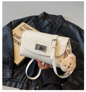 Detail view of cream vintage pillow bag with silver metal lock and cute bear charm