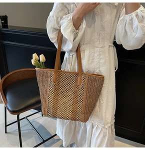 Detail view of straw tote bag with brown leather handles and hollow mesh lace decoration