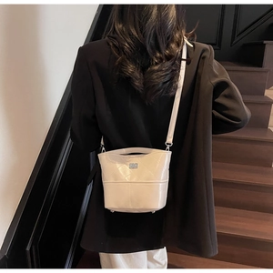 Dettaglio di una borsa a secchiello trapuntata bianca con tracolla su una modella