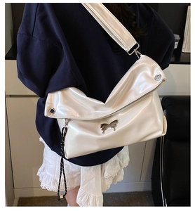 Détail du sac cabas en cuir verni blanc avec boucle papillon et œillets métalliques larges
