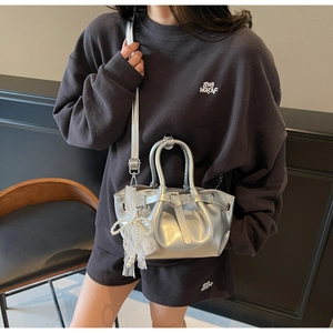 Silver metallic pleated bucket bag featuring a lace pearl bow pendant and dual straps