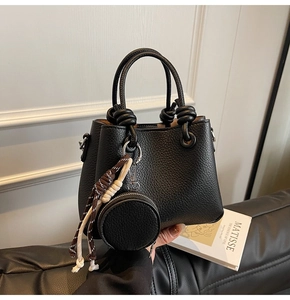 Detail of black lychee grain leather bucket bag with braided rope charm and coin purse