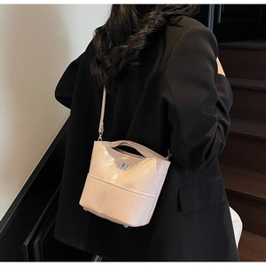 Dettaglio borsa a secchiello trapuntata rosa con tracolla indossata da una modella elegante