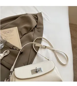 Detail view of the creamy white leather shoulder bag with its silver metal swivel lock buckle