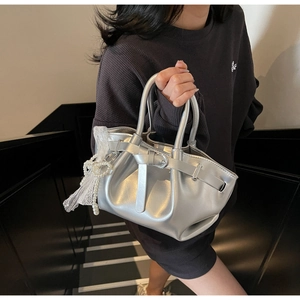 Detail of silver pleated bucket bag with pearl bow pendant and lace trim decoration