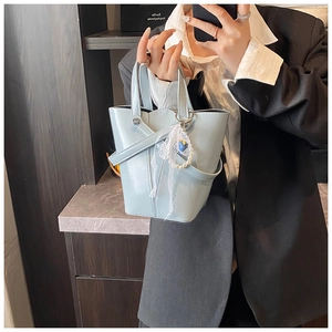 Détail du sac seau bleu clair en cuir huilé avec charm élégant en perles et dentelle raffinée