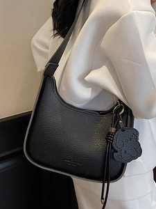 Elegant black lychee pattern hobo bag with a cute dog charm shown on shoulder