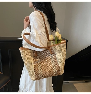 Detail of spacious straw tote bag featuring contrast colors and brown faux leather trim