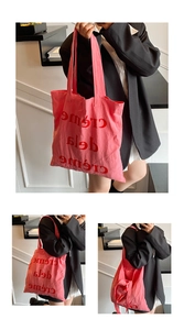 Détail du grand sac cabas en toile rose avec imprimé de lettres rouges et bandoulières