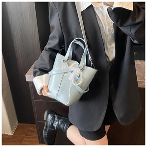 Détail du sac seau bleu clair brillant avec breloque perle et bandoulière amovible
