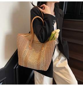 Detail of hand-woven straw tote bag with brown leather straps and hollow texture
