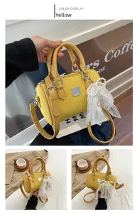 Detail of yellow woven pillow bag with leather handles and pearl bow charm accessory