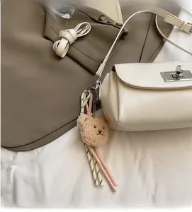 Detailed shot of cream white faux leather bag featuring metal lock and bear charm accessory